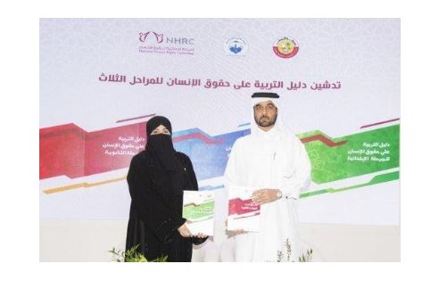 Two people show the new guide on human rights education developed in Qatar