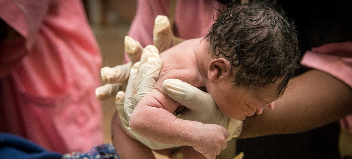 A baby is born into the careful hands of a nurse.