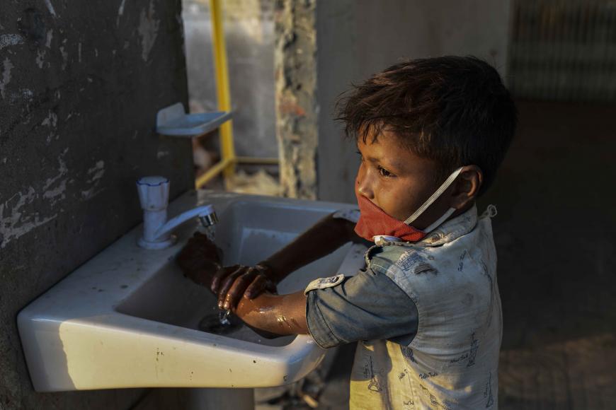 A little boy washes his dirty hands in the sink