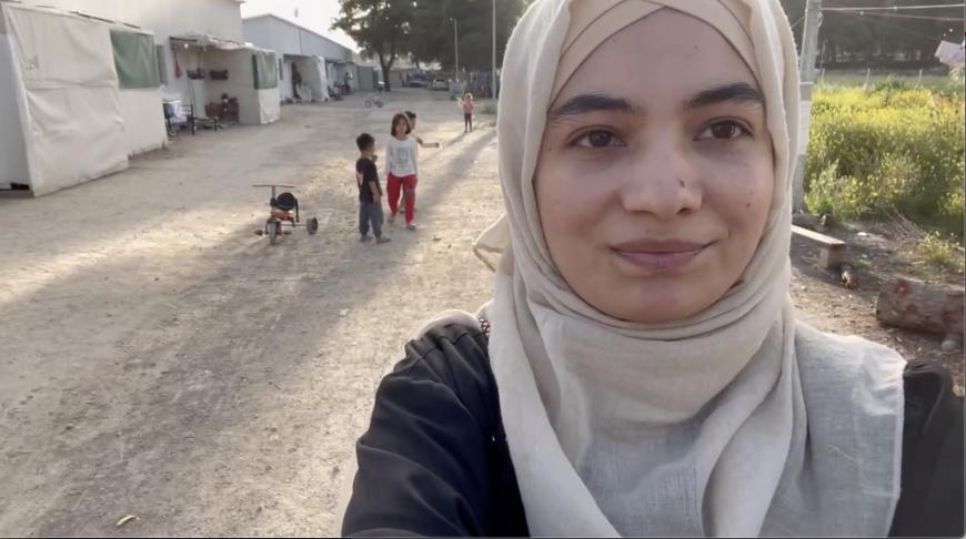 A girl takes a selfie of herself and some children in the refugee camp