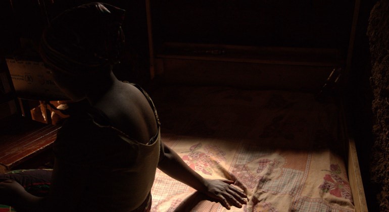 child sitting on a bed in a dark room